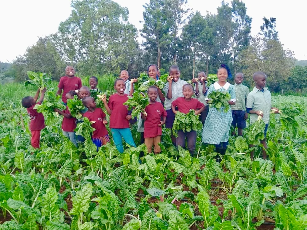 A group holding their leafy vegetable harvest.